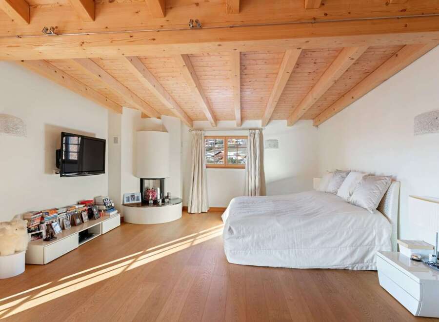 Experience cozy living in this charming bedroom featuring a modern fireplace and a large, comfortable bed.