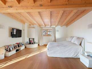Experience cozy living in this charming bedroom featuring a modern fireplace and a large, comfortable bed.