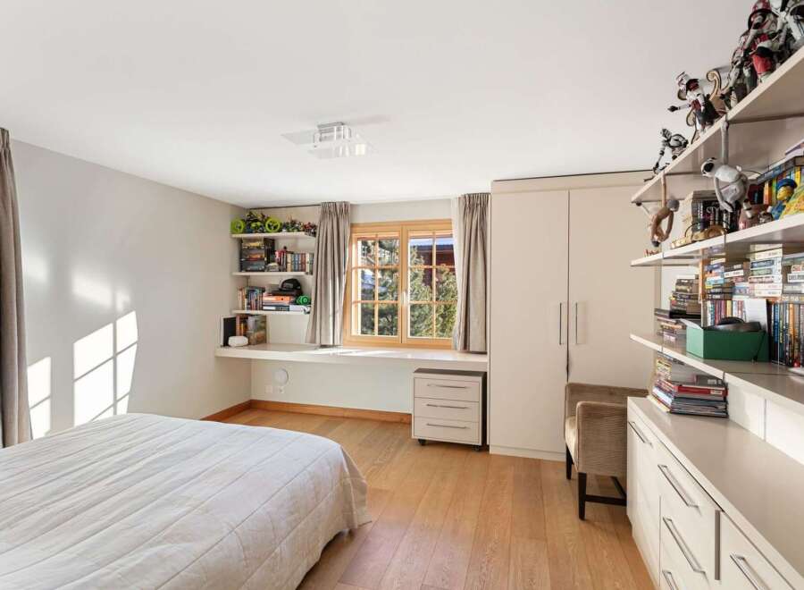 This charming bedroom features a built-in desk area with ample shelving, perfect for storage and display.