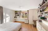 This charming bedroom features a built-in desk area with ample shelving, perfect for storage and display.