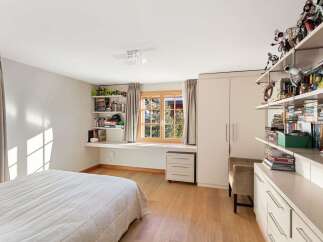 This charming bedroom features a built-in desk area with ample shelving, perfect for storage and display.