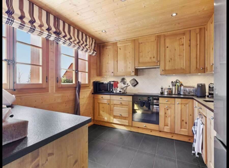 Experience rustic charm in this beautifully appointed wooden kitchen, featuring warm pine cabinetry and a sleek black countertop.