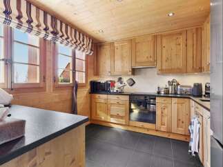 Experience rustic charm in this beautifully appointed wooden kitchen, featuring warm pine cabinetry and a sleek black countertop.