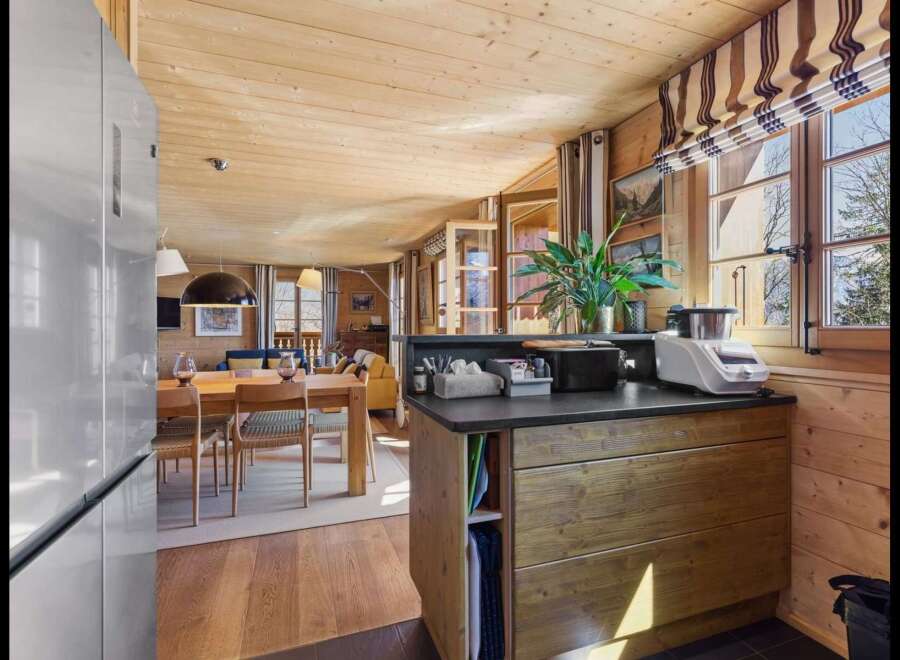 Experience cozy living in this charming wooden cabin, featuring a spacious dining area and a well-equipped kitchen island.