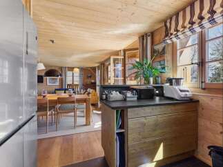 Experience cozy living in this charming wooden cabin, featuring a spacious dining area and a well-equipped kitchen island.
