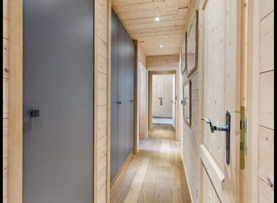 Step into this charming hallway featuring warm, natural wood paneling on the walls and ceiling, creating a cozy and inviting atmosphere.