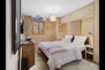 Experience rustic charm in this beautifully appointed bedroom, featuring warm, natural wood paneling throughout.