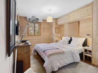 Experience rustic charm in this beautifully appointed bedroom, featuring warm, natural wood paneling throughout.