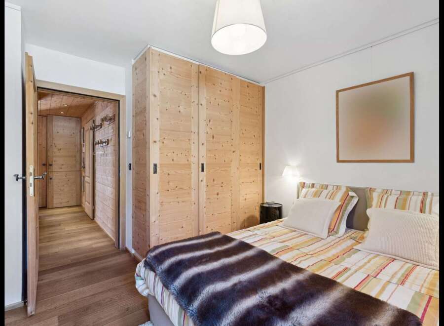 Experience rustic charm in this inviting bedroom, featuring a spacious wooden wardrobe and a cozy bed adorned with a plush throw.