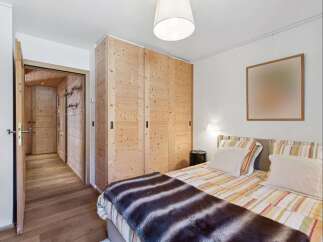 Experience rustic charm in this inviting bedroom, featuring a spacious wooden wardrobe and a cozy bed adorned with a plush throw.