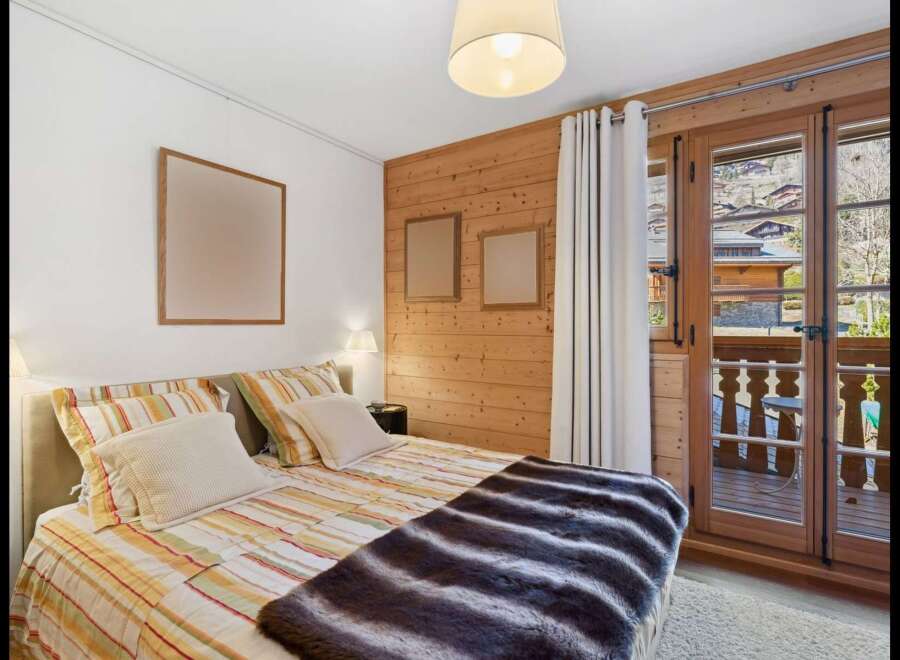 Experience cozy mountain living in this charming bedroom featuring a comfortable bed adorned with striped linens and a plush faux fur throw.