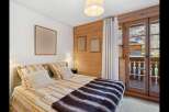 Experience cozy mountain living in this charming bedroom featuring a comfortable bed adorned with striped linens and a plush faux fur throw.