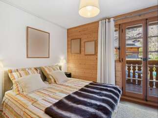 Experience cozy mountain living in this charming bedroom featuring a comfortable bed adorned with striped linens and a plush faux fur throw.
