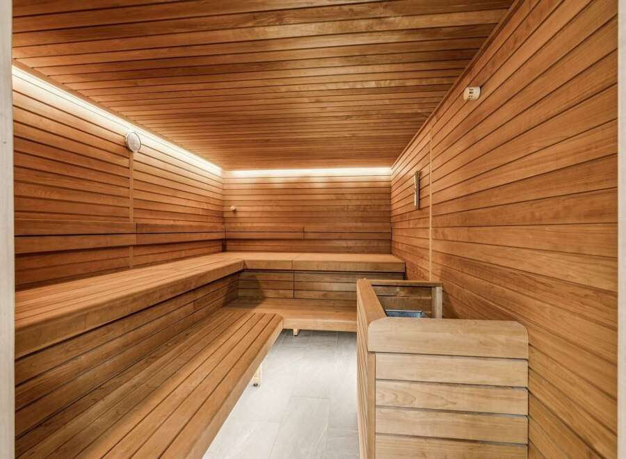 Experience ultimate relaxation in this luxurious wooden sauna, featuring multi-level seating and ambient LED lighting.