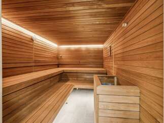Experience ultimate relaxation in this luxurious wooden sauna, featuring multi-level seating and ambient LED lighting.