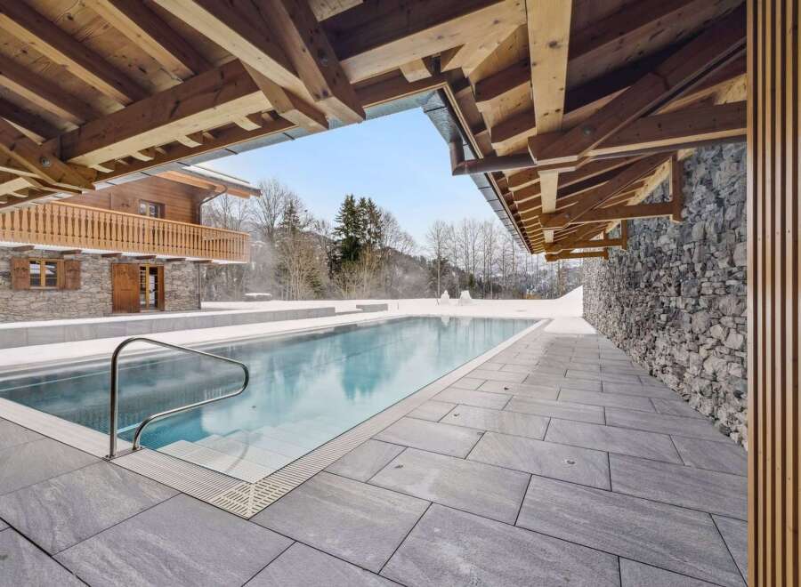Experience luxury in this stunning alpine retreat featuring an outdoor swimming pool surrounded by snow-covered landscapes.