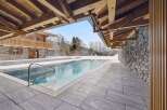 Experience luxury in this stunning alpine retreat featuring an outdoor swimming pool surrounded by snow-covered landscapes.