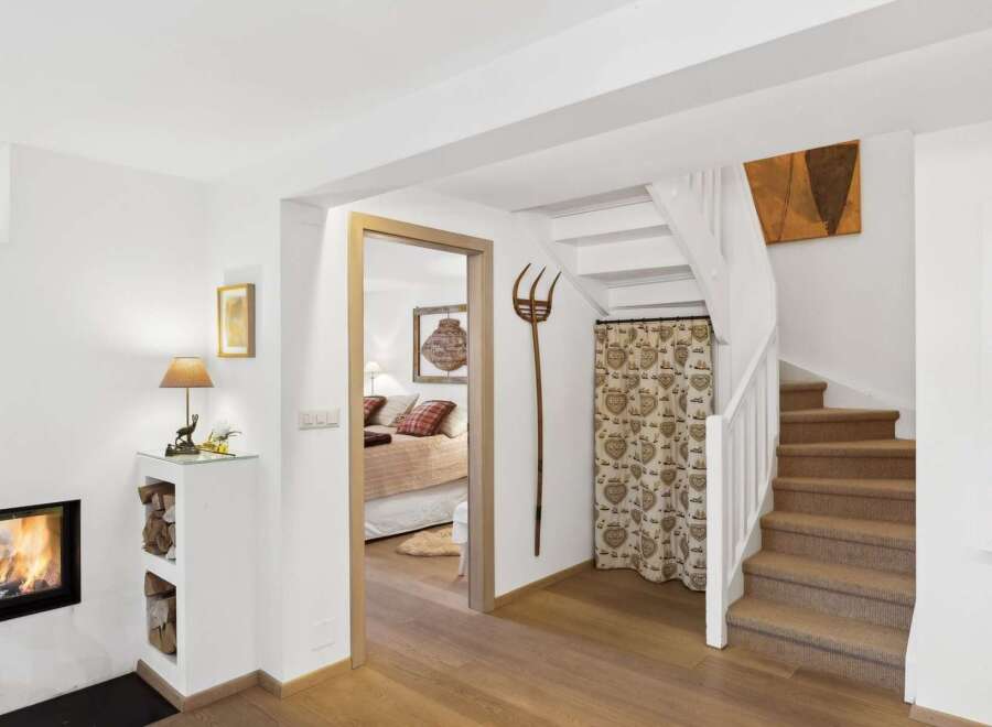 Discover a charming interior featuring a cozy fireplace and a well-lit bedroom accessible through a wooden doorway.