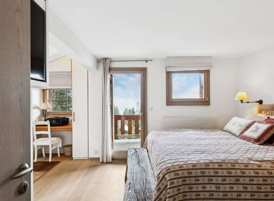 Experience cozy mountain living in this charming bedroom featuring a comfortable bed adorned with decorative pillows and a rustic wooden bench.