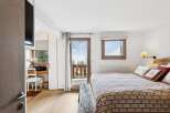 Experience cozy mountain living in this charming bedroom featuring a comfortable bed adorned with decorative pillows and a rustic wooden bench.