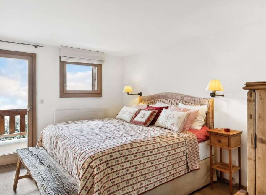 Experience cozy mountain living in this charming bedroom featuring a comfortable bed adorned with decorative pillows and a rustic quilt.