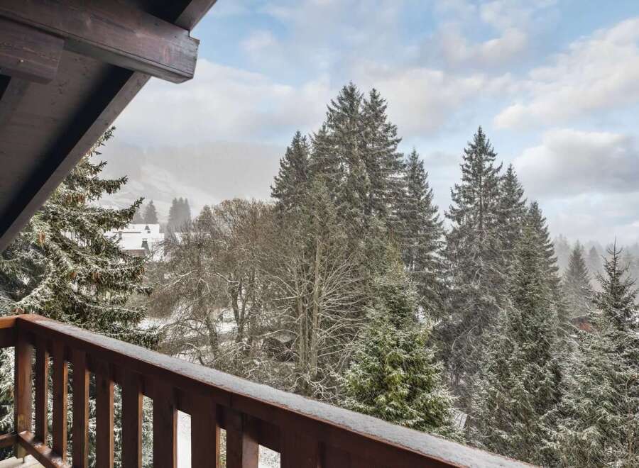 Experience the charm of a winter wonderland from your private balcony, offering breathtaking views of snow-dusted pine trees and a serene mountain landscape.