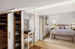 Discover this charming bedroom featuring a built-in wardrobe with ample storage and a convenient desk area by the window.