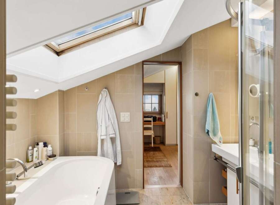 Experience luxury in this attic bathroom featuring a deep soaking tub and a separate glass-enclosed shower.