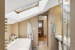 Experience luxury in this attic bathroom featuring a deep soaking tub and a separate glass-enclosed shower.