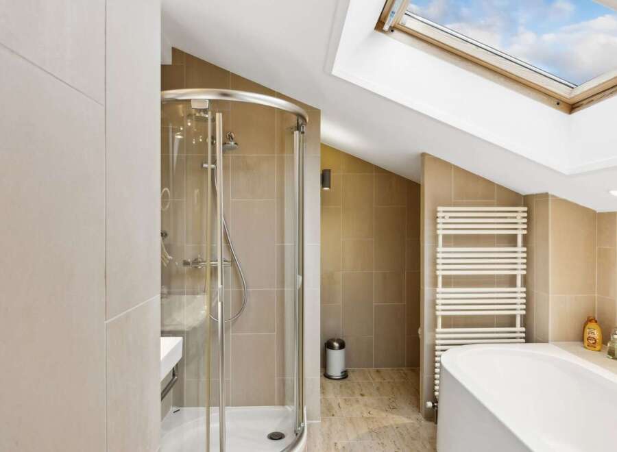 Experience modern luxury in this stunning bathroom featuring a sleek glass-enclosed shower and a deep soaking tub, perfect for relaxation.
