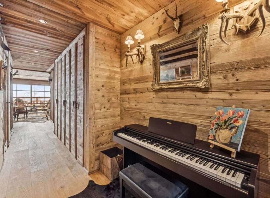 Experience rustic charm in this mountain retreat, featuring a cozy hallway adorned with wooden paneling and a grand piano for musical evenings.