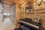 Experience rustic charm in this mountain retreat, featuring a cozy hallway adorned with wooden paneling and a grand piano for musical evenings.