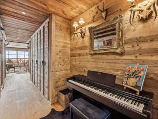 Experience rustic charm in this mountain retreat, featuring a cozy hallway adorned with wooden paneling and a grand piano for musical evenings.
