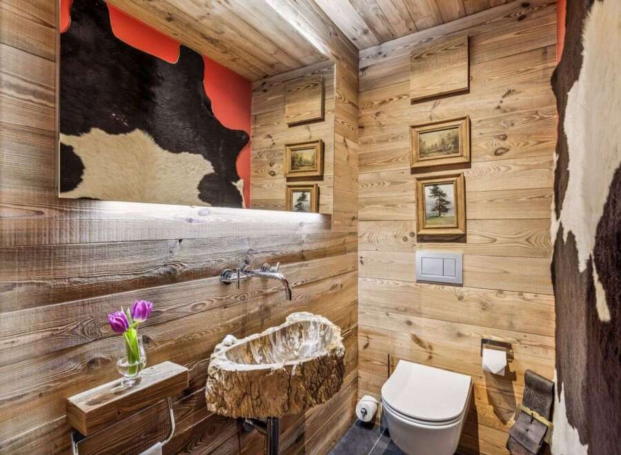 Experience rustic luxury in this unique bathroom featuring a stunning live-edge wood sink and walls clad in warm, natural wood.