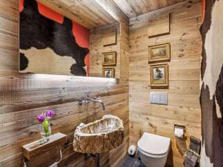 Experience rustic luxury in this unique bathroom featuring a stunning live-edge wood sink and walls clad in warm, natural wood.