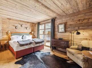 Experience rustic luxury in this charming bedroom, featuring warm wood paneling throughout and a cozy king-sized bed adorned with plush linens and decorative throws.