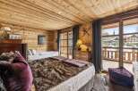 Experience rustic charm in this cozy mountain bedroom, featuring warm wood paneling throughout and a luxurious faux fur throw on the main bed.