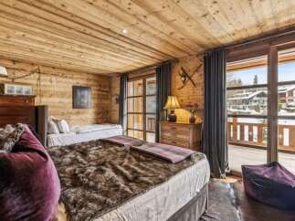 Experience rustic charm in this cozy mountain bedroom, featuring warm wood paneling throughout and a luxurious faux fur throw on the main bed.