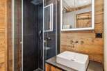 Experience modern alpine living in this beautifully appointed bathroom, featuring a sleek glass-enclosed shower with a rainfall showerhead and dark stone tiling.
