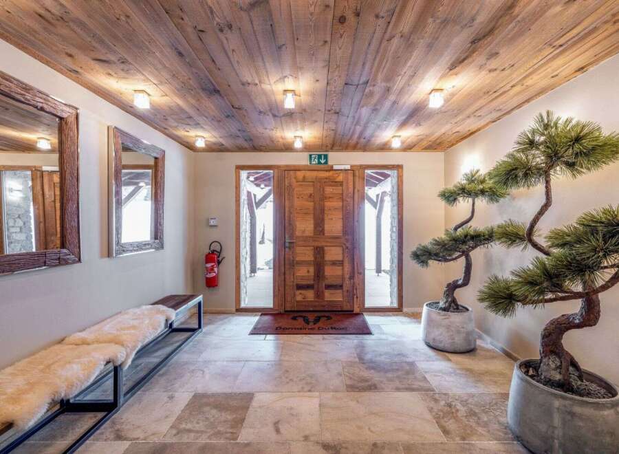 Step into a warm and inviting entryway featuring a rustic wooden ceiling and stone tile flooring.