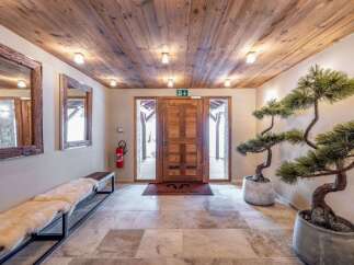 Step into a warm and inviting entryway featuring a rustic wooden ceiling and stone tile flooring.