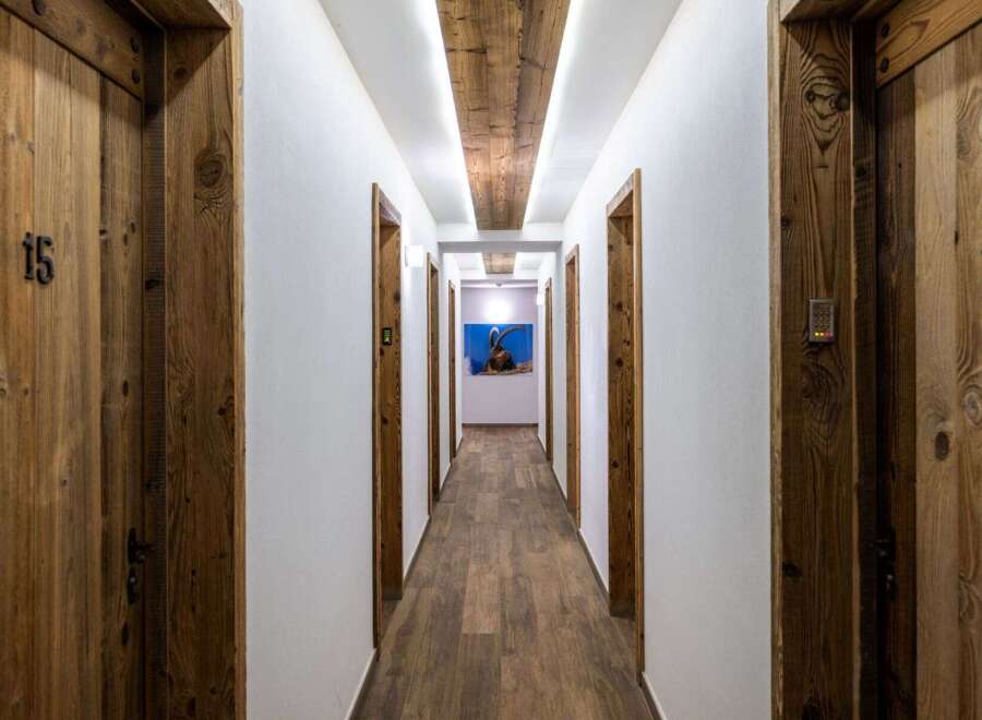 Experience rustic charm and modern convenience in this hotel hallway, featuring beautifully crafted wooden doors with unique numbering.