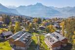 Experience luxury mountain living in this stunning alpine village, nestled amidst vibrant autumn foliage and majestic peaks.
