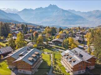 Experience luxury mountain living in this stunning alpine village, nestled amidst vibrant autumn foliage and majestic peaks.