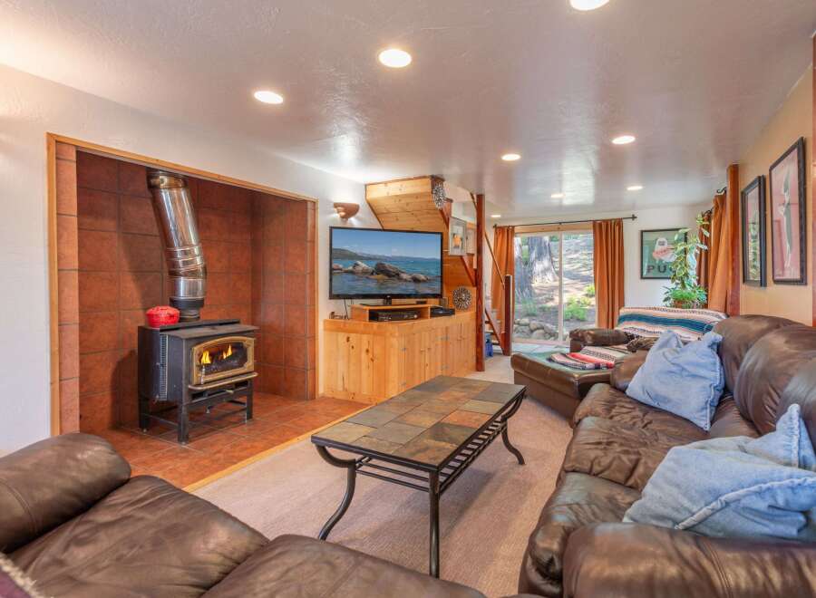 Cozy up by the fire in this inviting living room, featuring a rustic wood-burning stove set against a warm tile backdrop.