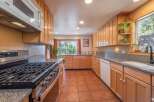 This spacious kitchen features light wood cabinetry, granite countertops, and a gas range perfect for cooking enthusiasts.
