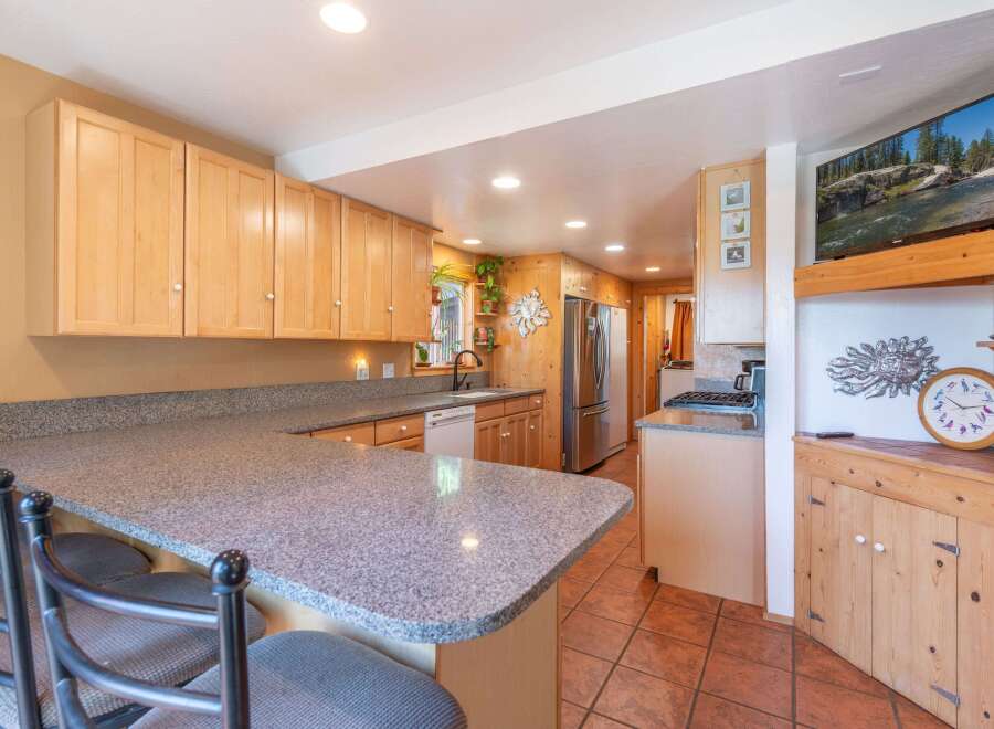 This charming kitchen features light wood cabinetry and a spacious granite countertop, perfect for meal preparation and casual dining.