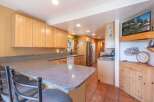 This charming kitchen features light wood cabinetry and a spacious granite countertop, perfect for meal preparation and casual dining.