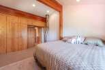 Experience rustic charm in this cozy bedroom featuring a large wooden wardrobe and a comfortable bed adorned with decorative pillows.