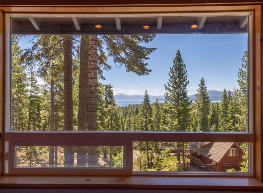 Experience breathtaking lake and mountain views from this stunning property, framed by a lush forest of mature pine trees.